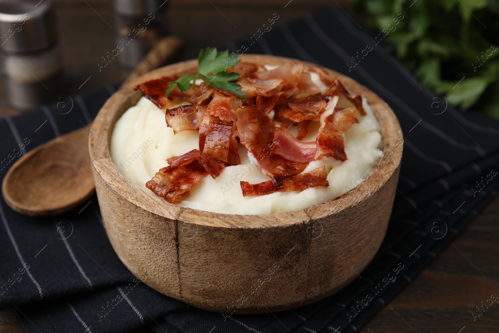 Photo of Fried bacon, mashed potato and parsley in bowl on table, closeup