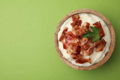 Photo of Fried bacon, mashed potato and parsley in bowl on green background, top view. Space for text