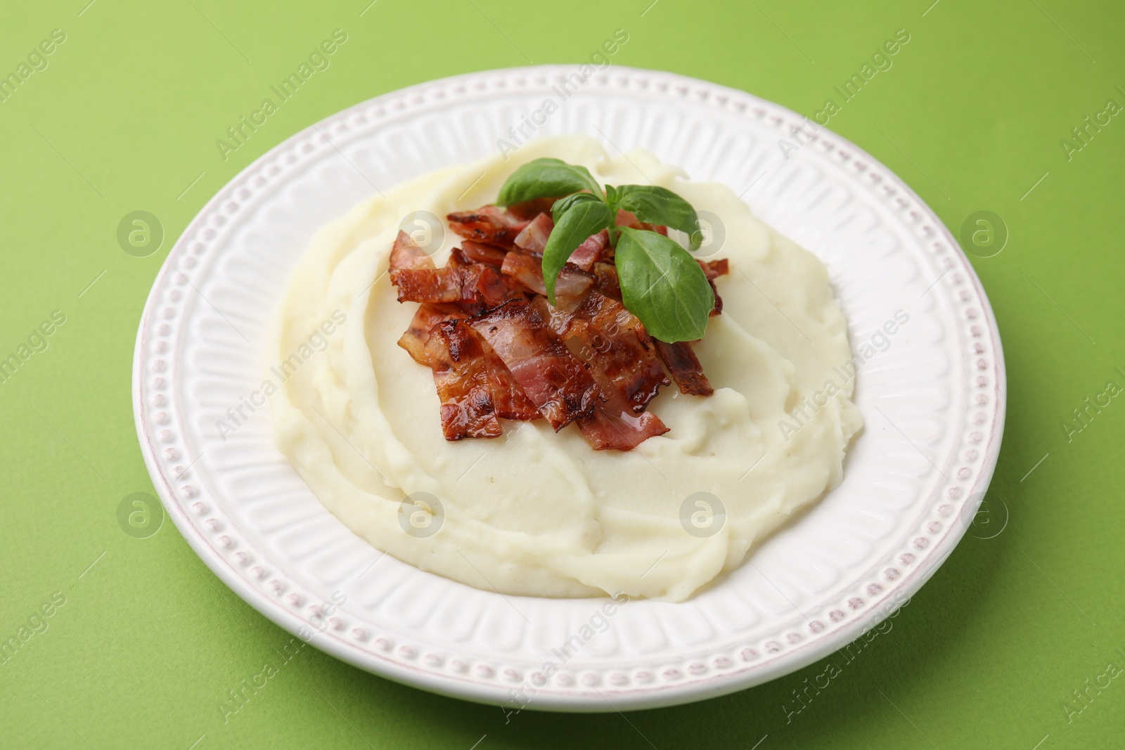 Photo of Fried bacon, mashed potato and basil on green background