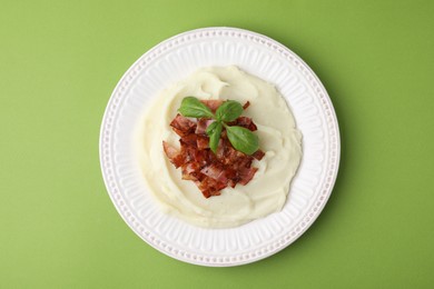 Photo of Fried bacon, mashed potato and basil on green background, top view