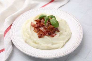 Fried bacon, mashed potato and basil on white tiled table