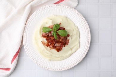 Photo of Fried bacon, mashed potato and basil on white tiled table, top view