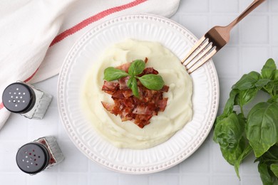 Fried bacon, mashed potato, basil and fork on white tiled table, top view