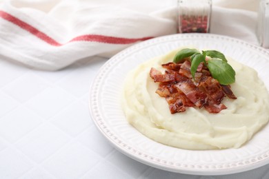 Fried bacon, mashed potato and basil on white tiled table, space for text