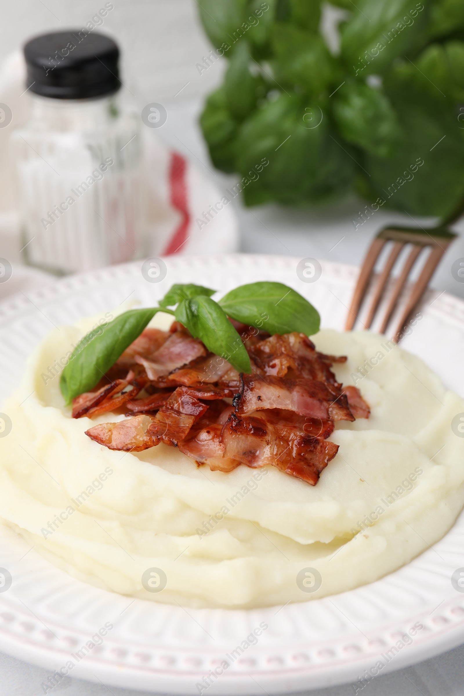 Photo of Fried bacon, mashed potato, basil and fork on table, closeup