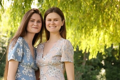 Photo of Portrait of two beautiful twin sisters in park, space for text
