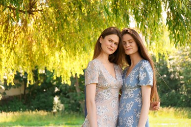 Photo of Portrait of two beautiful twin sisters in park, space for text