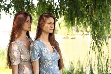 Portrait of two beautiful twin sisters in park, space for text