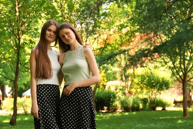 Portrait of two beautiful twin sisters in park, space for text
