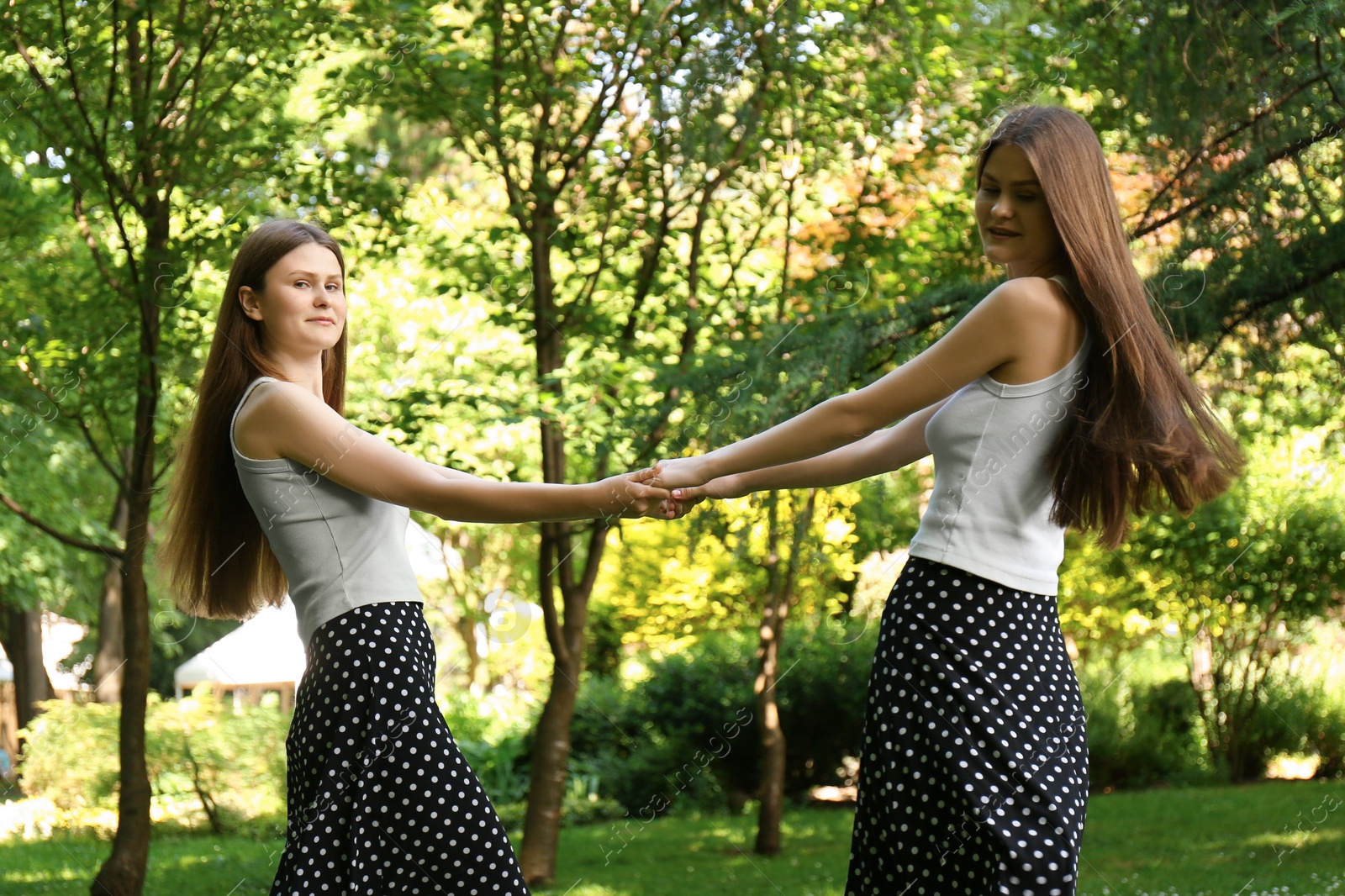 Photo of Two beautiful twin sisters spending time together in park