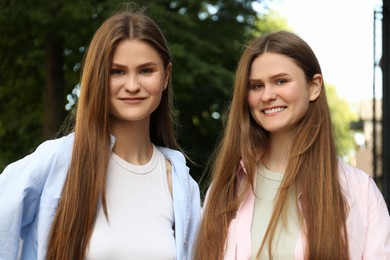 Photo of Portrait of two beautiful twin sisters outdoors