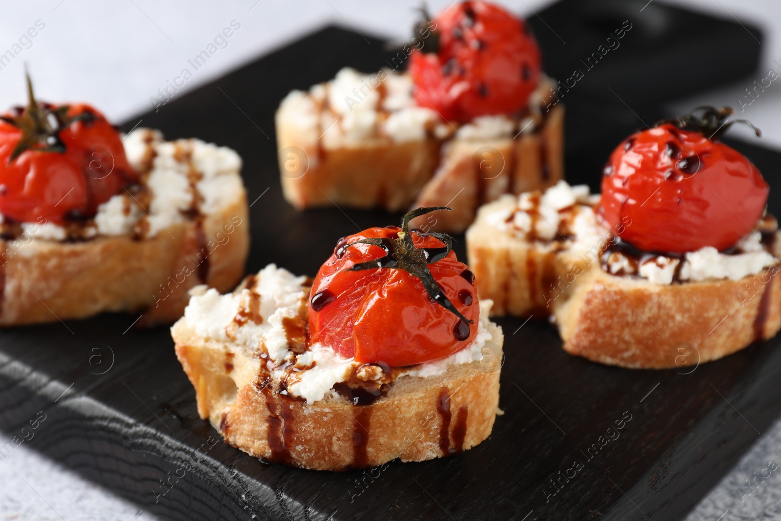 Photo of Bruschettas with ricotta cheese, tomatoes and balsamic sauce on grey table, closeup