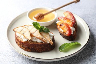 Photo of Delicious bruschettas with ricotta cheese and honey on light grey table, closeup