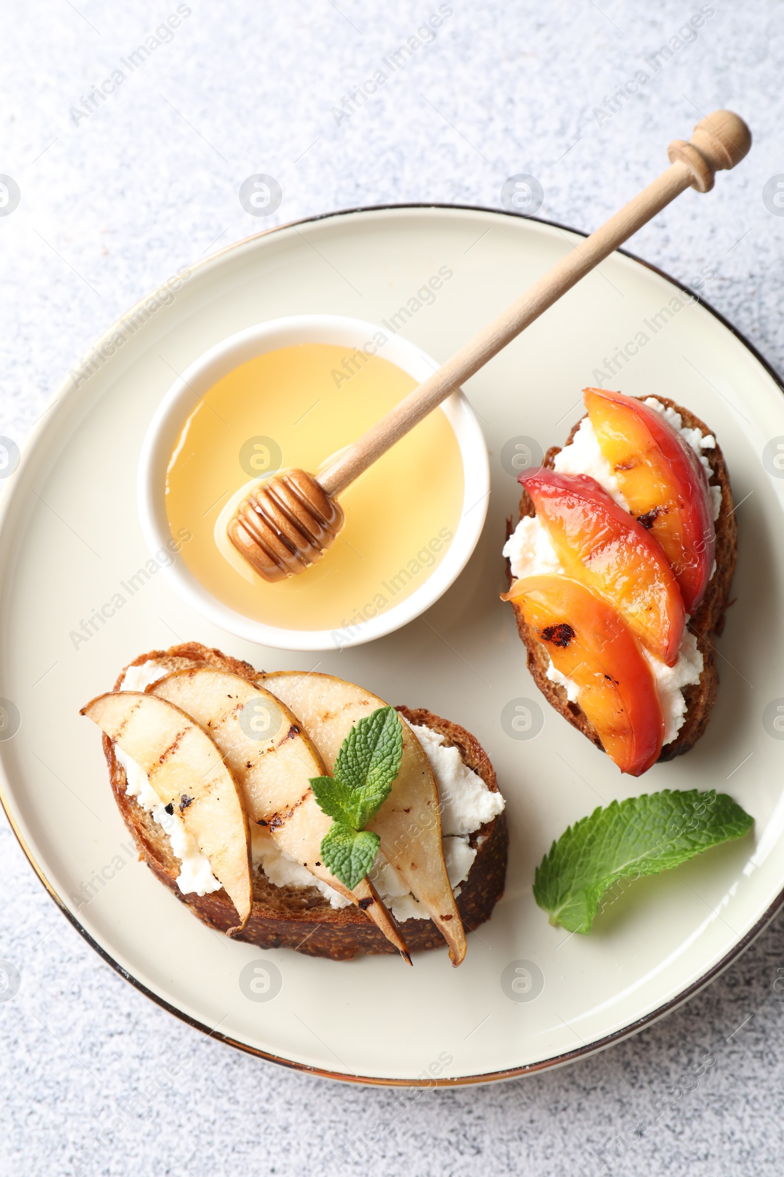 Photo of Delicious bruschettas with ricotta cheese and honey on light grey table, top view