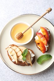 Photo of Delicious bruschettas with ricotta cheese and honey on light grey table, top view