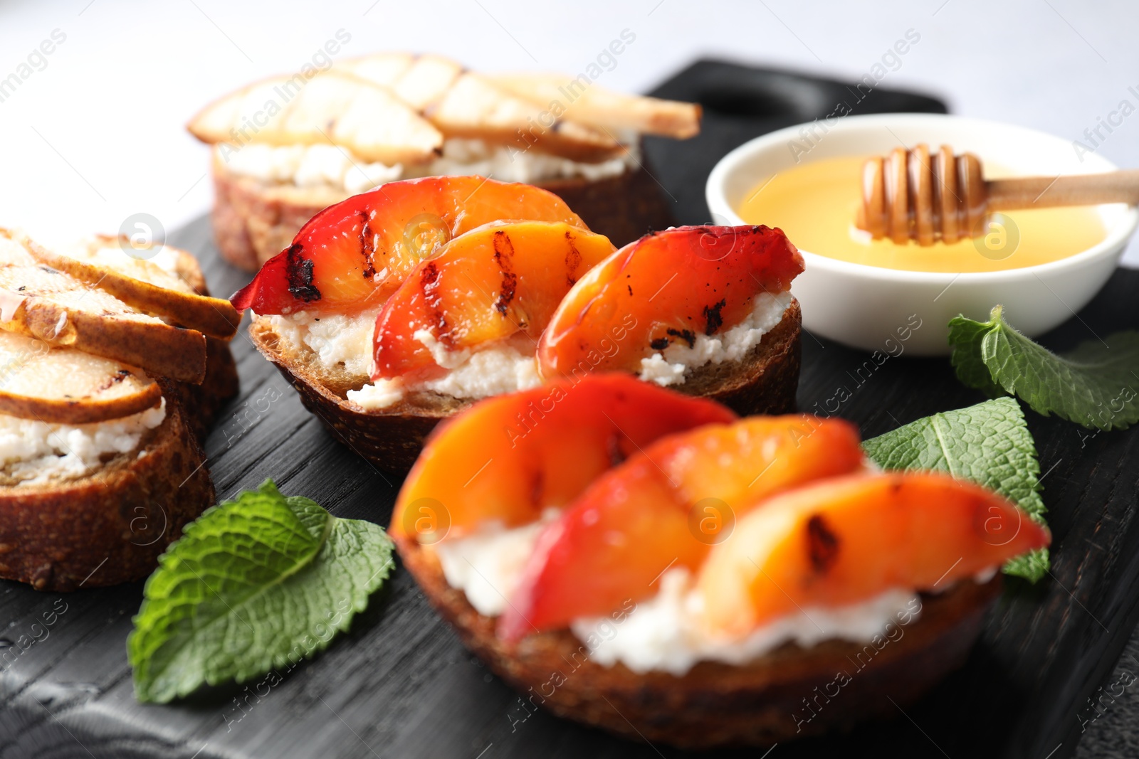 Photo of Delicious bruschettas with ricotta cheese and honey on light grey table, closeup