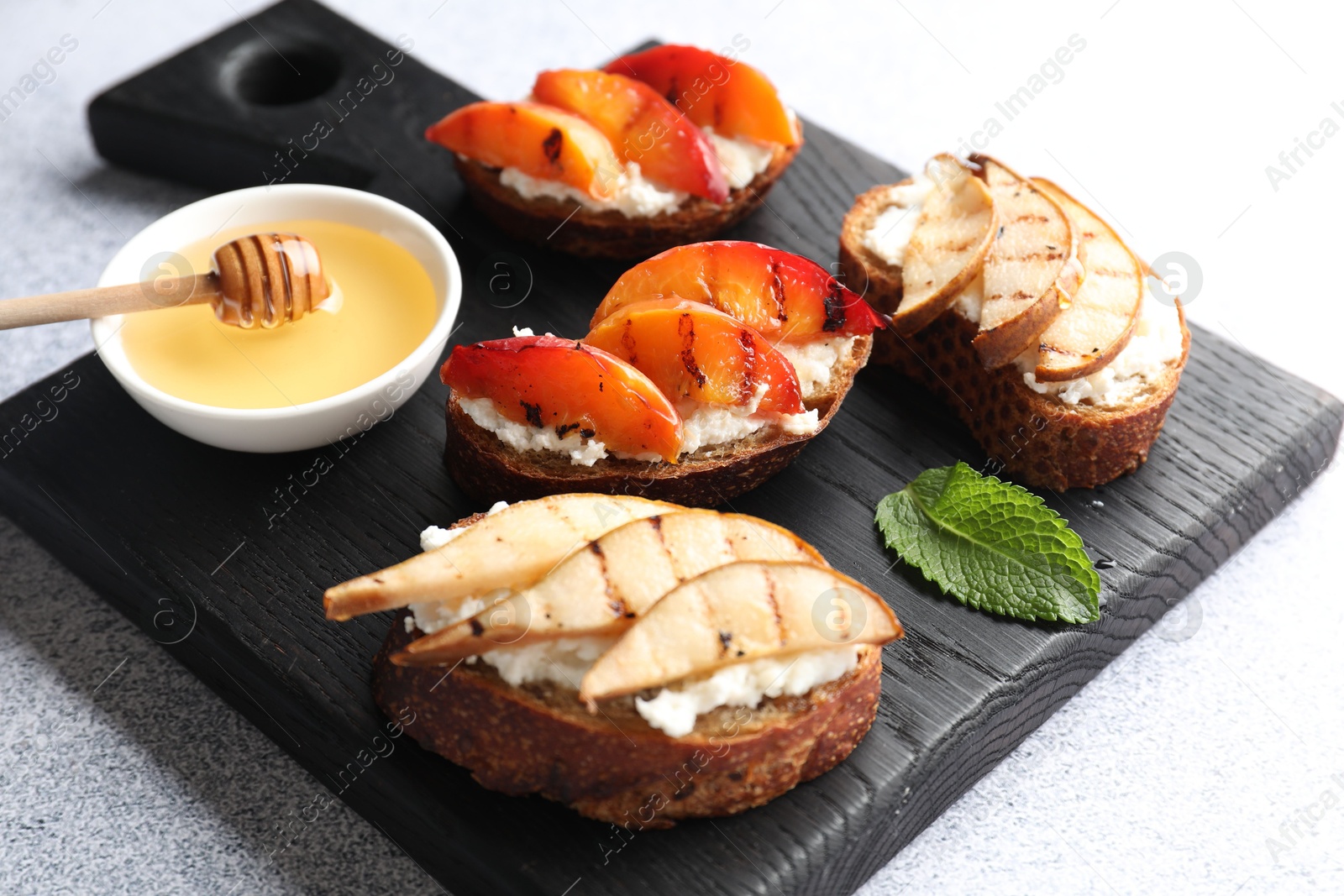 Photo of Delicious bruschettas with ricotta cheese and honey on light grey table, closeup