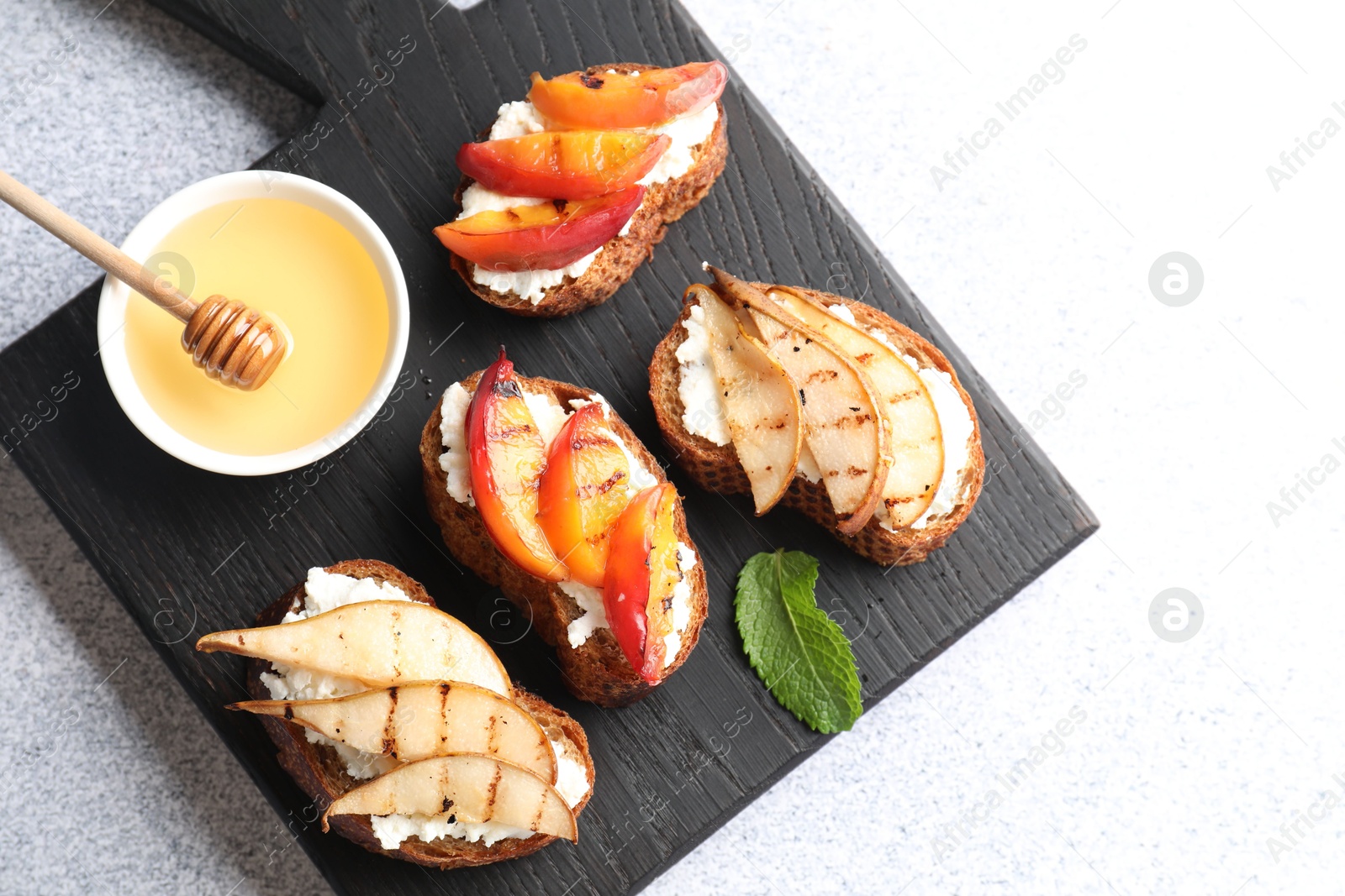 Photo of Delicious bruschettas with ricotta cheese and honey on light grey table, top view