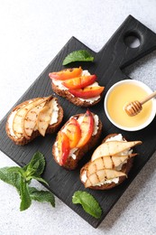 Delicious bruschettas with ricotta cheese and honey on light grey table, top view