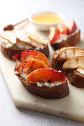 Delicious bruschettas with ricotta cheese and honey on light grey table, closeup