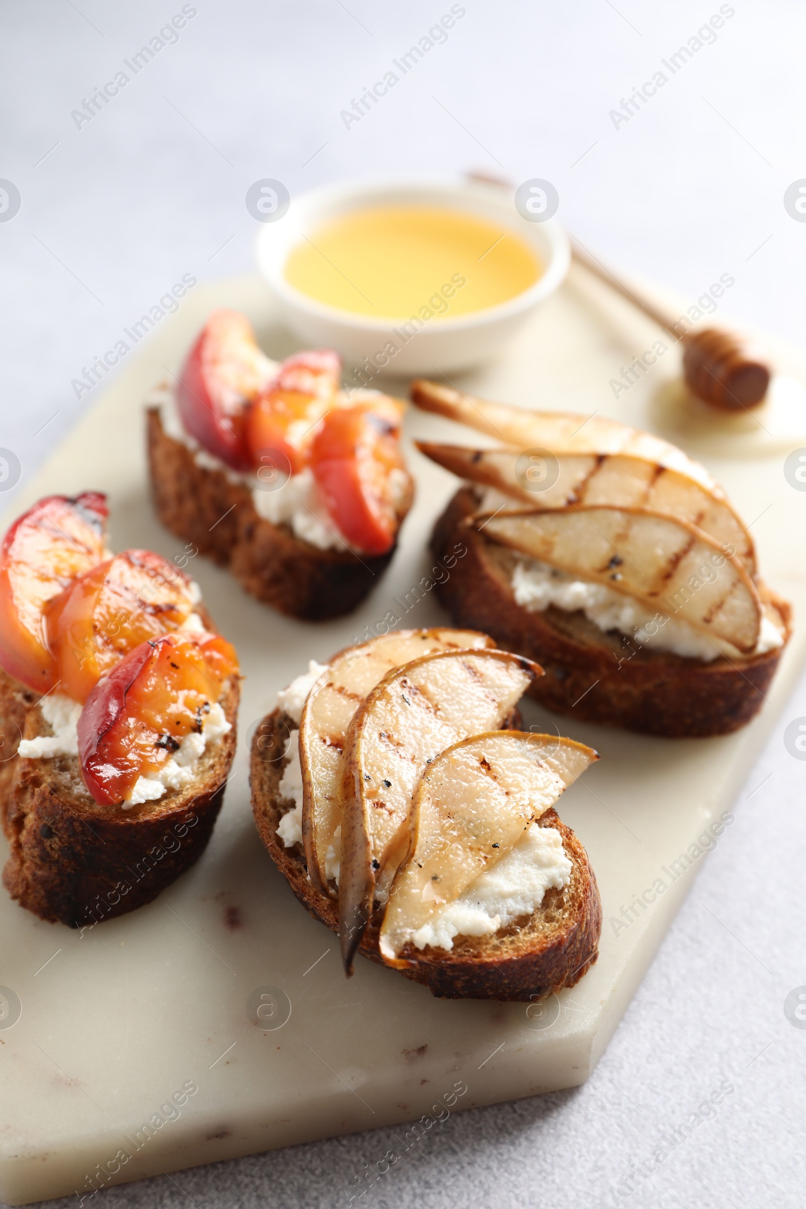 Photo of Delicious bruschettas with ricotta cheese and honey on light grey table, closeup