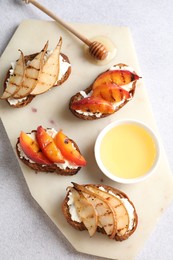 Photo of Delicious bruschettas with ricotta cheese and honey on light grey table, top view