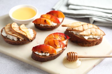 Photo of Delicious bruschettas with ricotta cheese and honey on light grey table, closeup