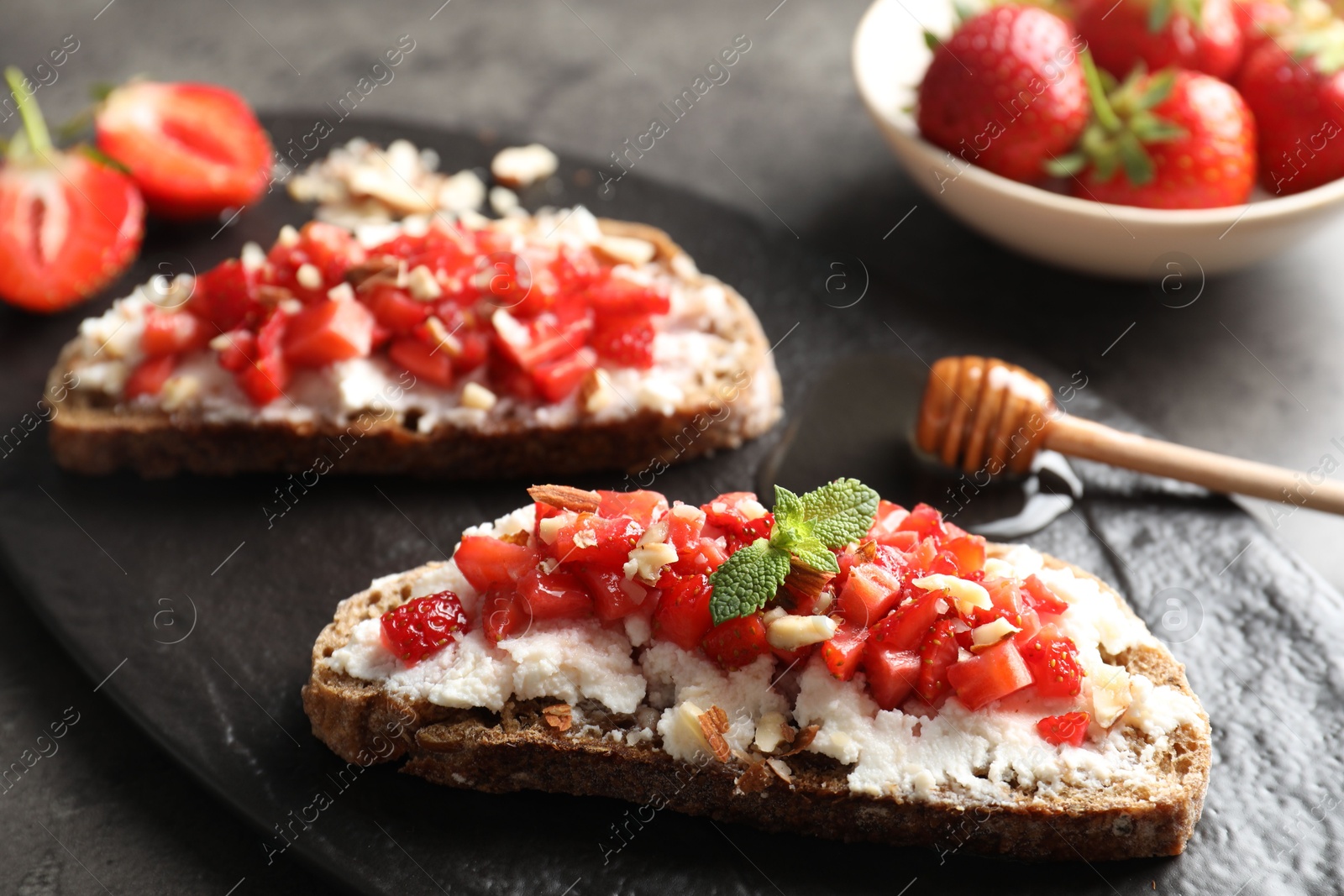 Photo of Bruschettas with ricotta cheese, chopped strawberries and mint on table, closeup