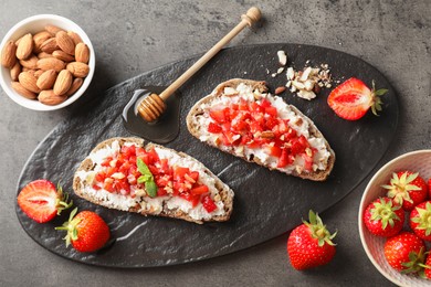 Photo of Bruschettas with ricotta cheese, chopped strawberries, nuts and mint on table, top view
