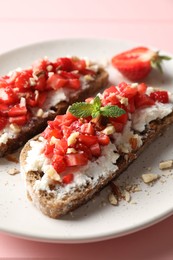 Bruschettas with ricotta cheese, chopped strawberries and mint on pink wooden table, closeup