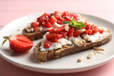 Bruschettas with ricotta cheese, chopped strawberries and mint on pink wooden table, closeup