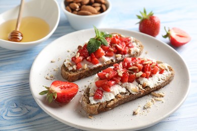 Photo of Bruschettas with ricotta cheese, chopped strawberries and mint on blue wooden table, closeup