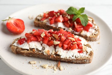 Bruschettas with ricotta cheese, chopped strawberries and mint on white wooden table, closeup