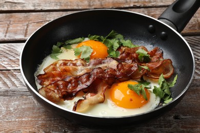 Photo of Tasty bacon, eggs and parsley in frying pan on wooden table, closeup