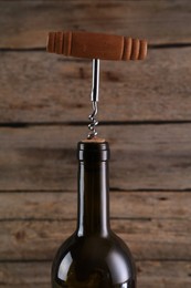 Wine bottle with corkscrew on wooden background