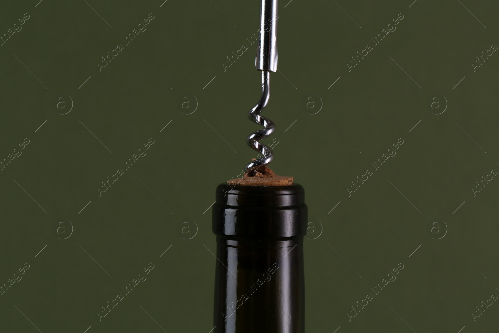 Photo of Wine bottle with corkscrew on olive background, closeup