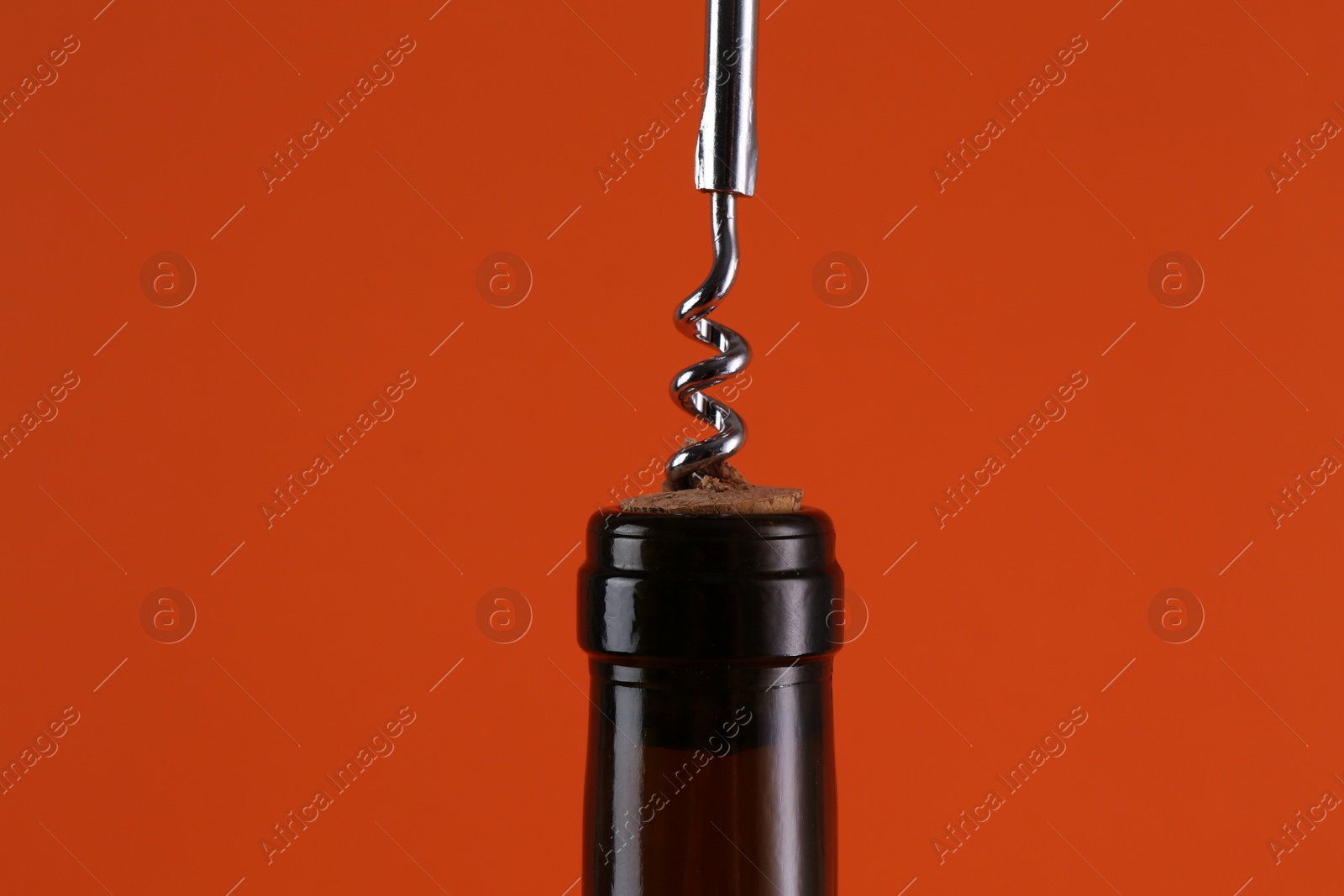 Photo of Wine bottle with corkscrew on orange background, closeup