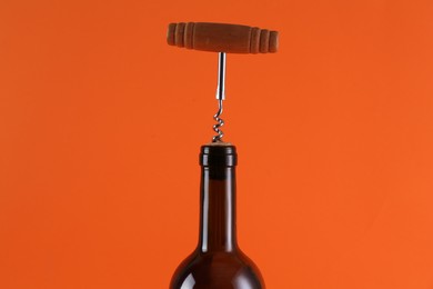 Photo of Wine bottle with corkscrew on orange background