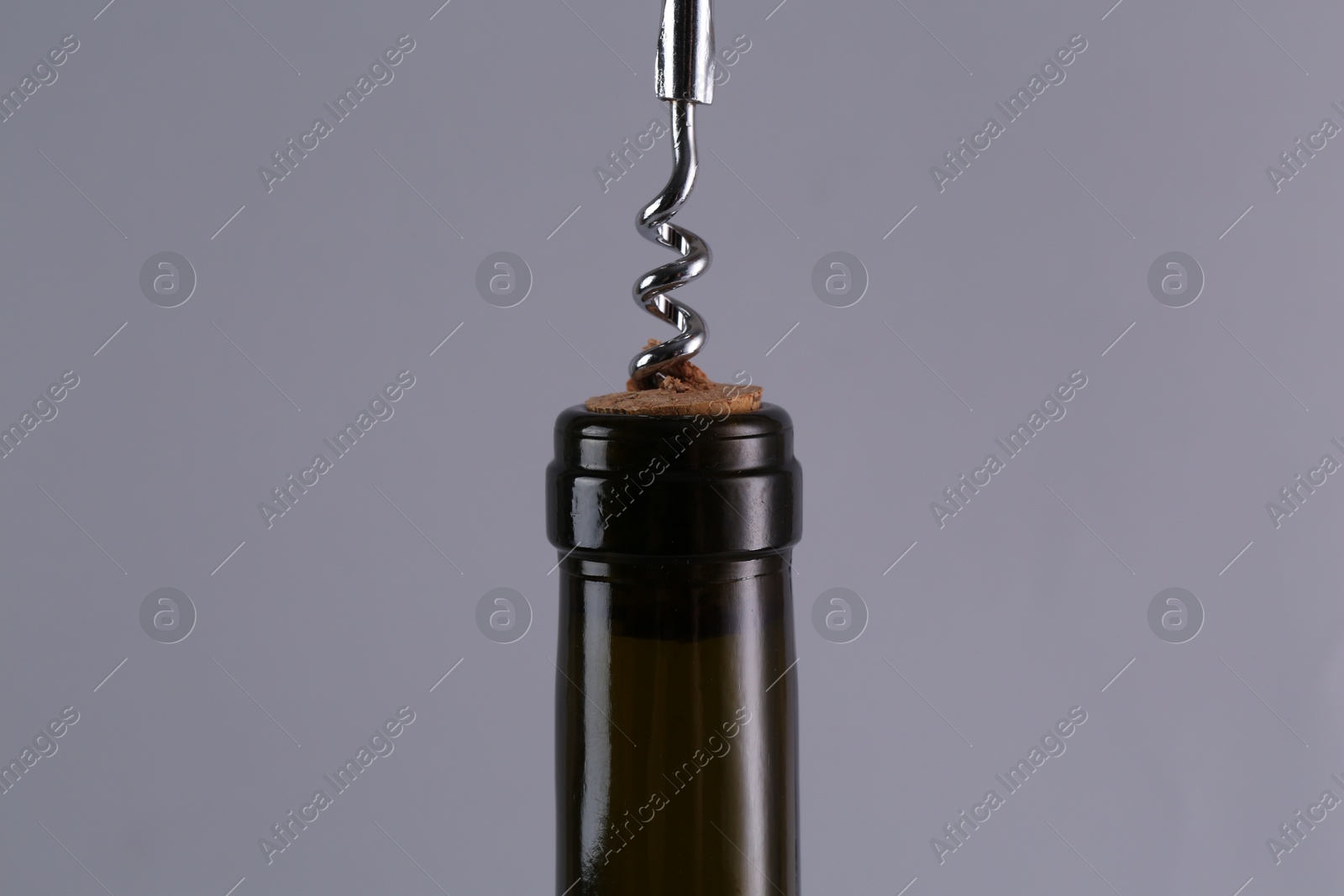 Photo of Wine bottle with corkscrew on grey background, closeup