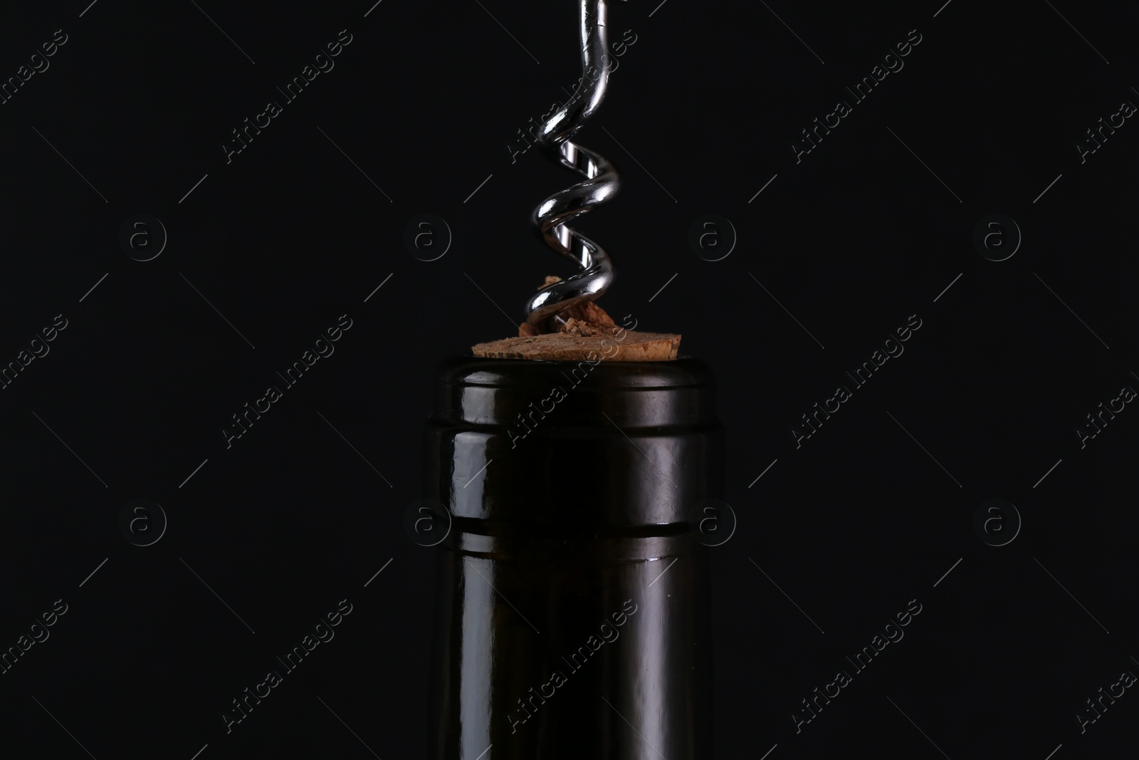 Photo of Wine bottle with corkscrew on black background, closeup