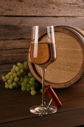 Glass of wine, corkscrew, barrel and grapes on wooden table