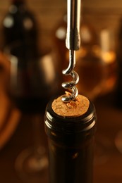 Wine bottle with corkscrew on blurred background, closeup