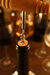 Photo of Wine bottle with corkscrew on blurred background, closeup