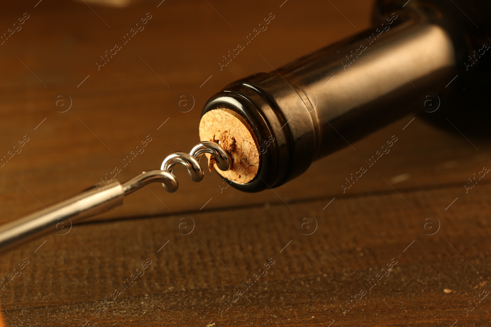 Photo of Wine bottle with corkscrew on wooden table, closeup