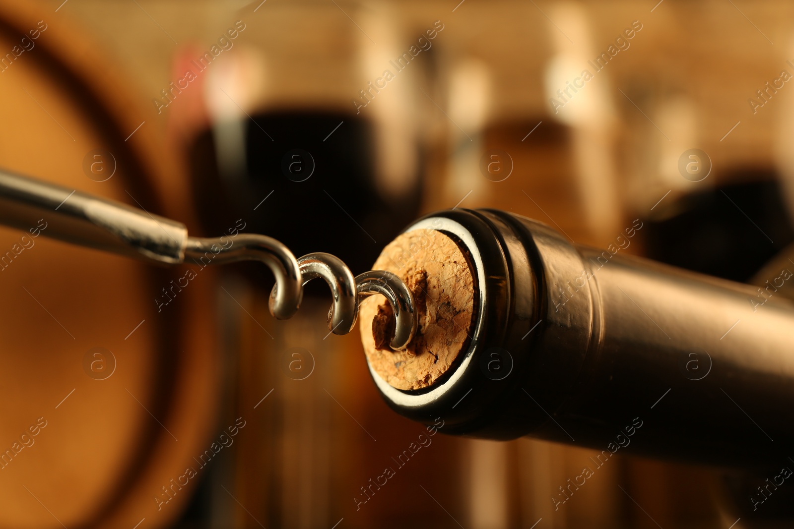 Photo of Wine bottle with corkscrew on blurred background, closeup