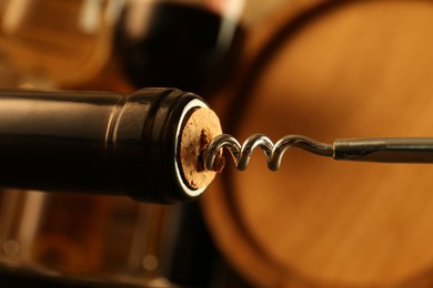 Wine bottle with corkscrew on blurred background, closeup