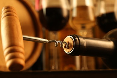 Photo of Wine bottle with corkscrew on blurred background, closeup