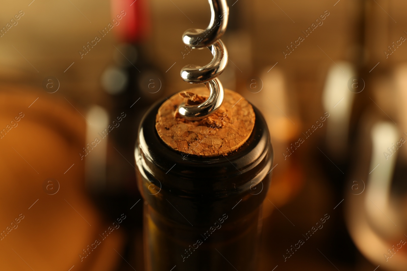 Photo of Wine bottle with corkscrew on blurred background, closeup