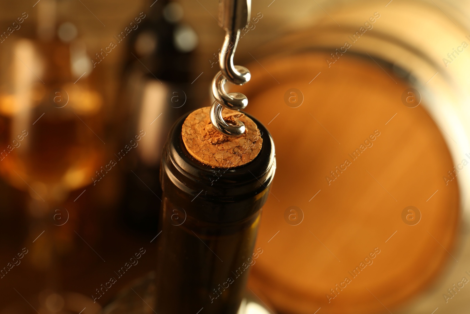 Photo of Wine bottle with corkscrew on blurred background, closeup