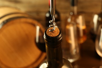 Wine bottle with corkscrew on blurred background, closeup